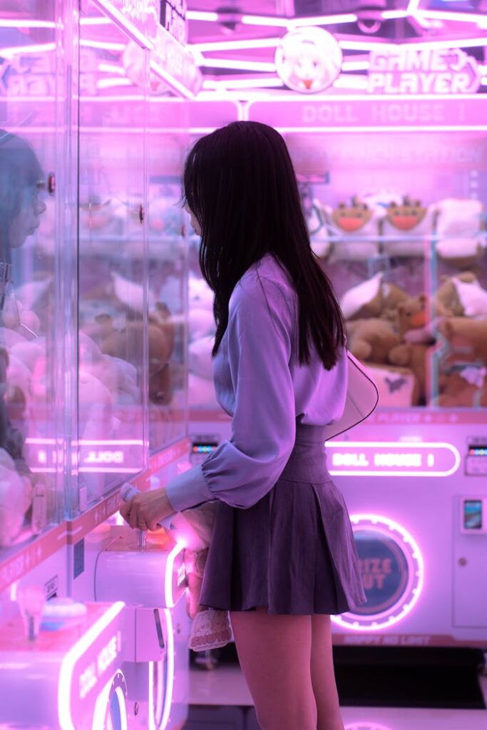 pexels-photo-25025685 A young woman enjoying a claw machine game in a vibrant Seoul arcade.